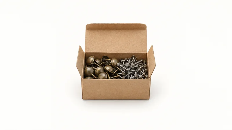 Isolated a box of upholstery tacks and gimp pins centred on a seamless pale off-white studio background, generous empty margin on every side for overlaid branding