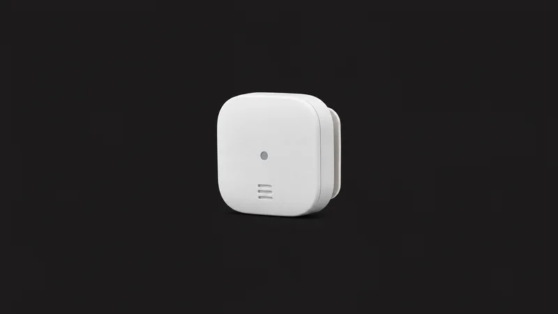 Isolated a small self-adhesive home telematics beacon in a white shell centred on a seamless deep charcoal near-black studio background, generous empty margin on every side for overlaid branding