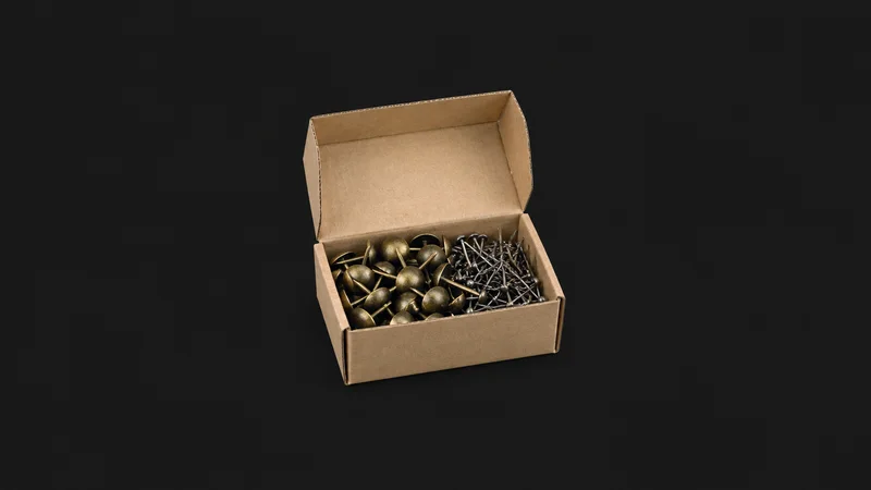 Isolated a box of upholstery tacks and gimp pins centred on a seamless deep charcoal near-black studio background, generous empty margin on every side for overlaid branding