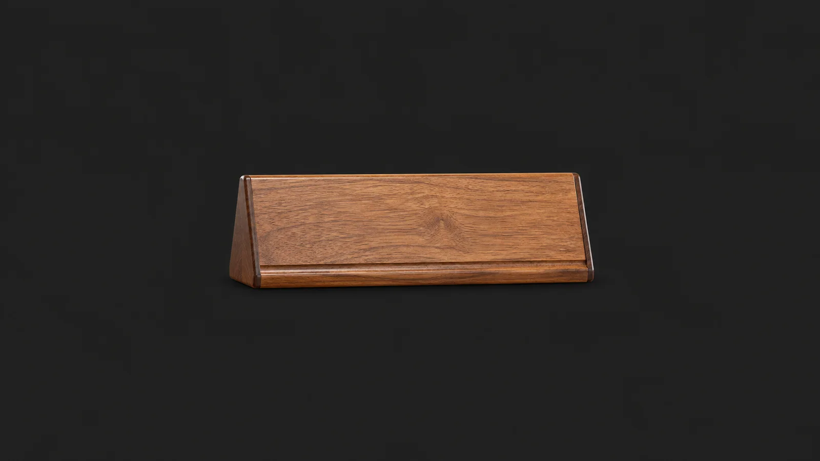 Isolated a wooden desk name-plate holder with no name centred on a seamless deep charcoal near-black studio background, generous empty margin on every side for overlaid branding