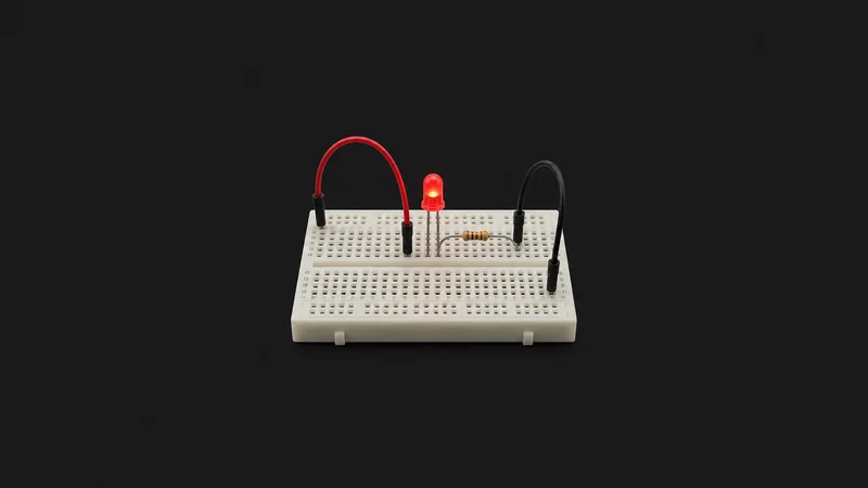 Isolated a breadboard wired with jumper leads and an LED centred on a seamless deep charcoal near-black studio background, generous empty margin on every side for overlaid branding