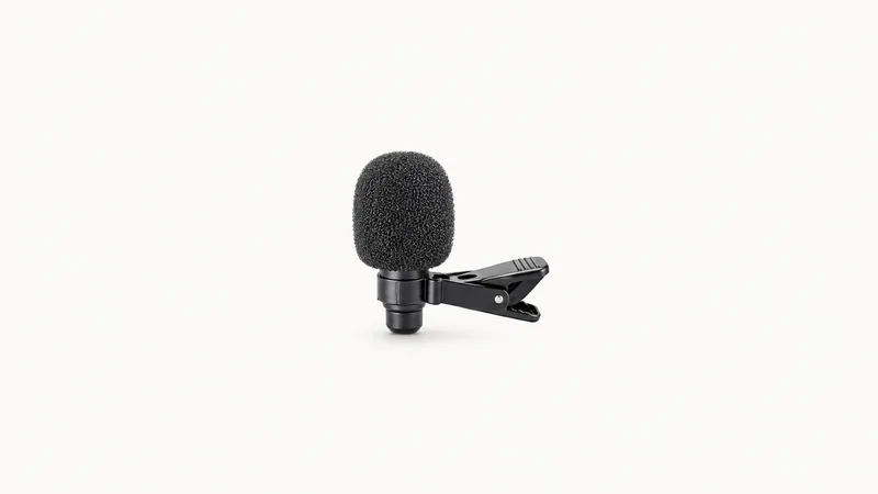 Isolated a compact clip-on lapel microphone with a windshield centred on a seamless pale off-white studio background, generous empty margin on every side for overlaid branding