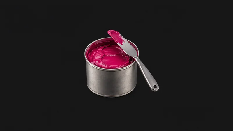 Isolated a tin of process-magenta offset ink with a palette knife centred on a seamless deep charcoal near-black studio background, generous empty margin on every side for overlaid branding