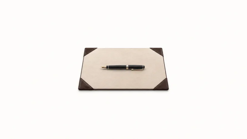 Isolated a leather-cornered desk blotter with a fountain pen centred on a seamless pale off-white studio background, generous empty margin on every side for overlaid branding