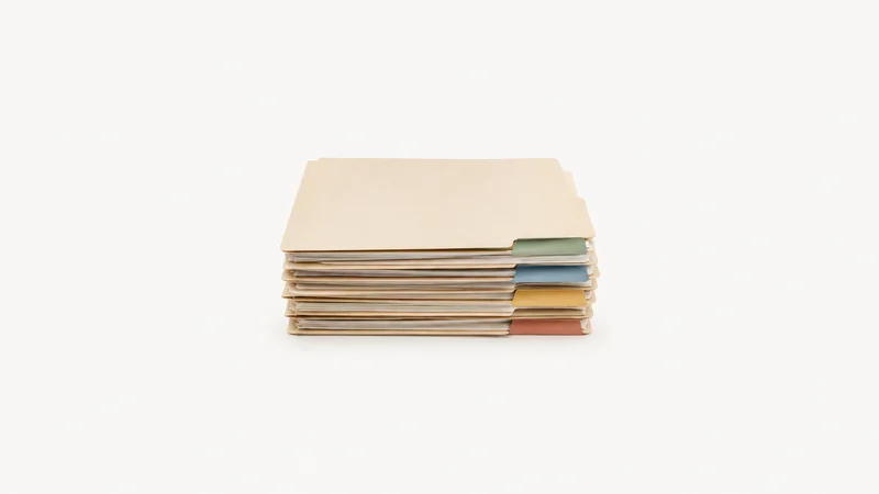 Isolated a stack of blank onboarding folders with colour tabs centred on a seamless pale off-white studio background, generous empty margin on every side for overlaid branding