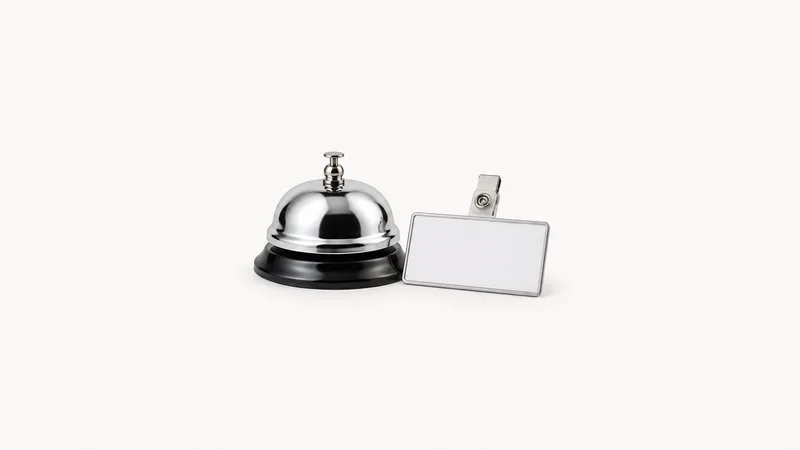 Isolated a chrome desk bell beside a blank name badge centred on a seamless pale off-white studio background, generous empty margin on every side for overlaid branding