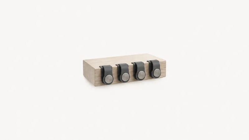 Isolated a set of magnetic cable clips on a desk edge centred on a seamless pale off-white studio background, generous empty margin on every side for overlaid branding