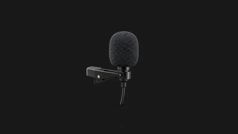 Isolated a compact clip-on lapel microphone with a windshield centred on a seamless deep charcoal near-black studio background, generous empty margin on every side for overlaid branding