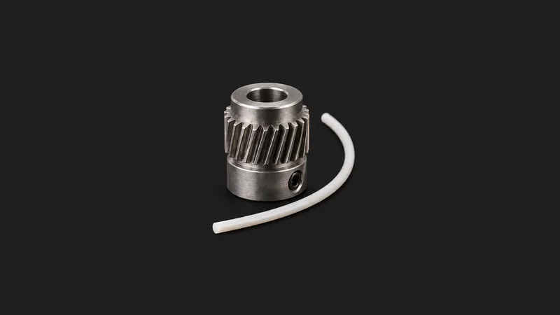 Isolated a hardened-steel direct-drive extruder gear beside a length of pla filament centred on a seamless deep charcoal near-black studio background, generous empty margin on every side for overlaid branding