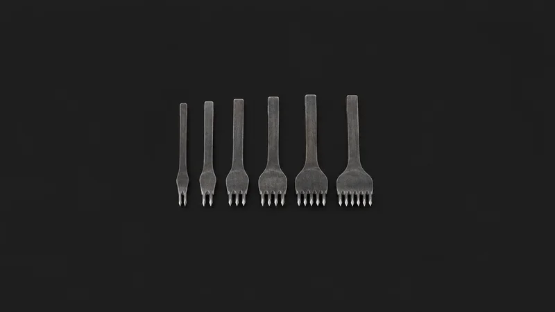 Isolated a set of pricking irons with diamond-shaped teeth laid in size order centred on a seamless deep charcoal near-black studio background, generous empty margin on every side for overlaid branding