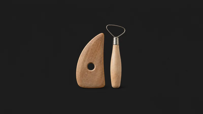 Isolated a wooden throwing rib and loop trimming tool pair centred on a seamless deep charcoal near-black studio background, generous empty margin on every side for overlaid branding