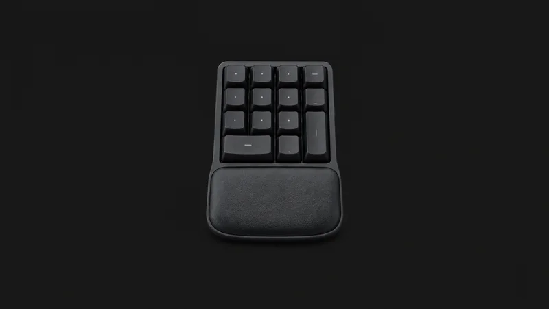 Isolated a compact ten-key numeric keypad with a wrist rest centred on a seamless deep charcoal near-black studio background, generous empty margin on every side for overlaid branding
