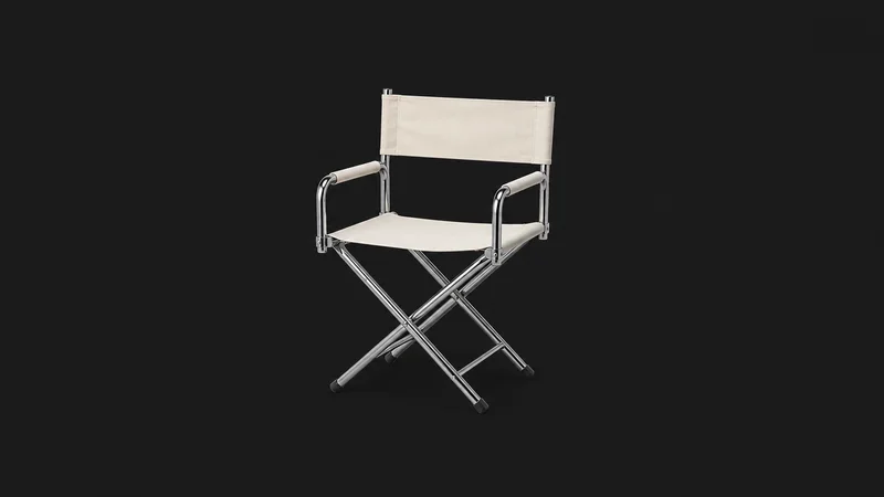 Isolated a chrome-legged director's chair with a blank canvas seat centred on a seamless deep charcoal near-black studio background, generous empty margin on every side for overlaid branding