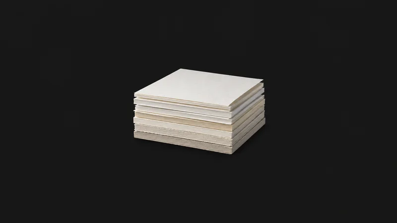 Isolated a stack of uncoated paper samples in graded weights centred on a seamless deep charcoal near-black studio background, generous empty margin on every side for overlaid branding