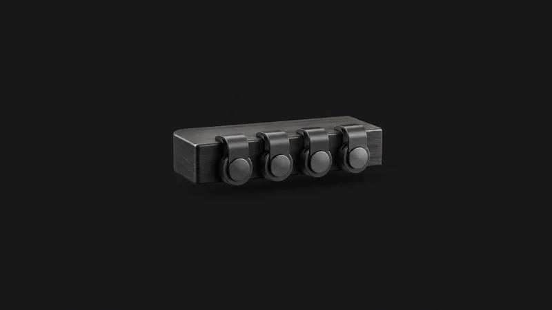 Isolated a set of magnetic cable clips on a desk edge centred on a seamless deep charcoal near-black studio background, generous empty margin on every side for overlaid branding