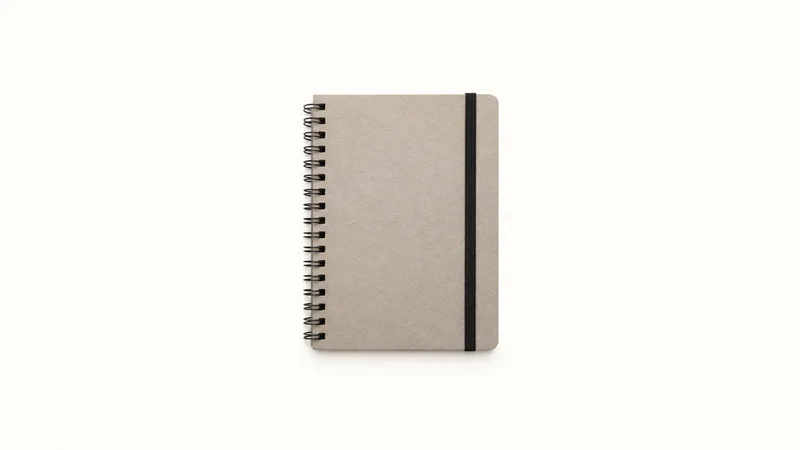 Isolated a spiral-bound blank reference notebook with a black elastic centred on a seamless pale off-white studio background, generous empty margin on every side for overlaid branding