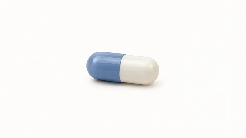 Isolated a coated two-tone gelatine capsule at close range centred on a seamless pale off-white studio background, generous empty margin on every side for overlaid branding