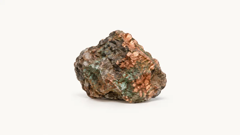 Isolated a sample of copper ore in a jagged chunk centred on a seamless pale off-white studio background, generous empty margin on every side for overlaid branding