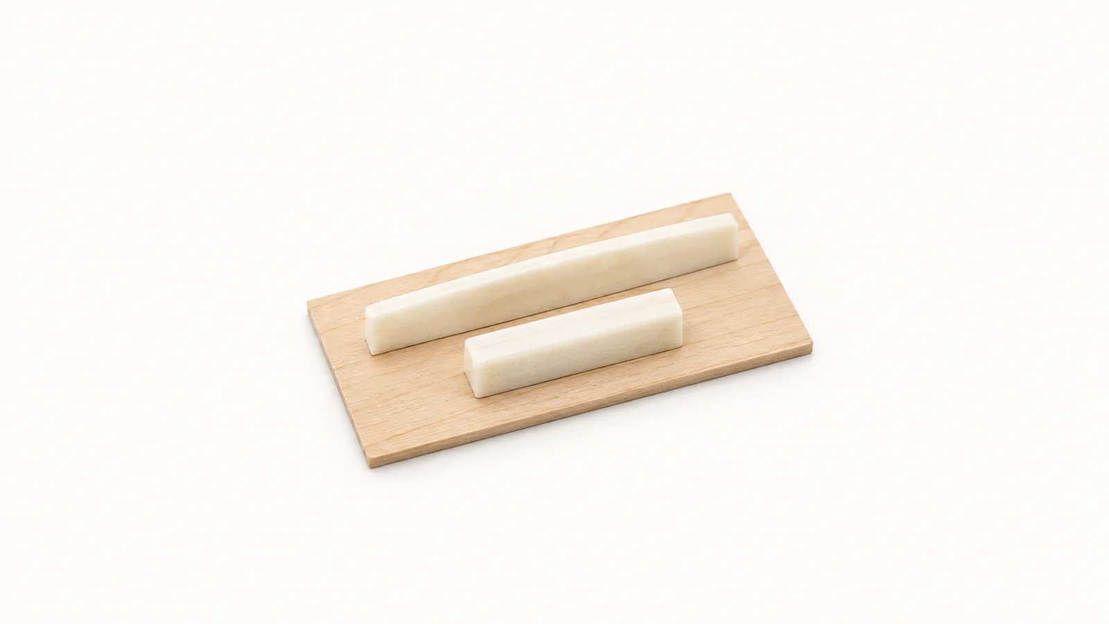 Isolated a bone nut and saddle blanks laid on a maple shim centred on a seamless pale off-white studio background, generous empty margin on every side for overlaid branding