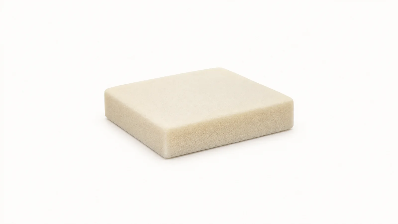 Isolated a slab of high-density foam cut to a cushion shape centred on a seamless pale off-white studio background, generous empty margin on every side for overlaid branding