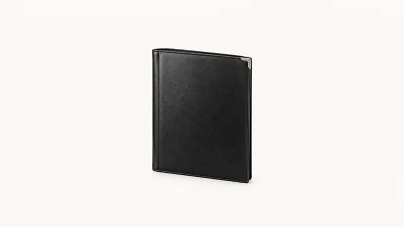 Isolated a black leather private banking folder with a silver corner centred on a seamless pale off-white studio background, generous empty margin on every side for overlaid branding