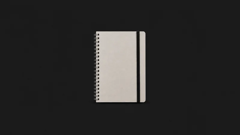 Isolated a spiral-bound blank reference notebook with a black elastic centred on a seamless deep charcoal near-black studio background, generous empty margin on every side for overlaid branding