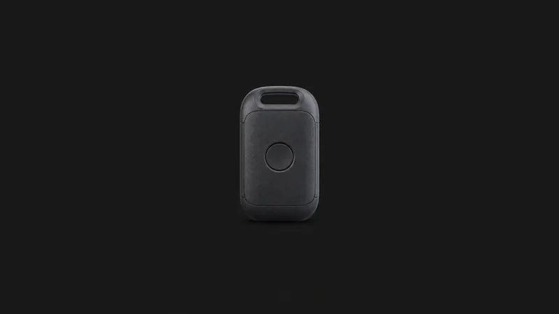 Isolated a shipment temperature-logger dongle with a single unmarked button centred on a seamless deep charcoal near-black studio background, generous empty margin on every side for overlaid branding