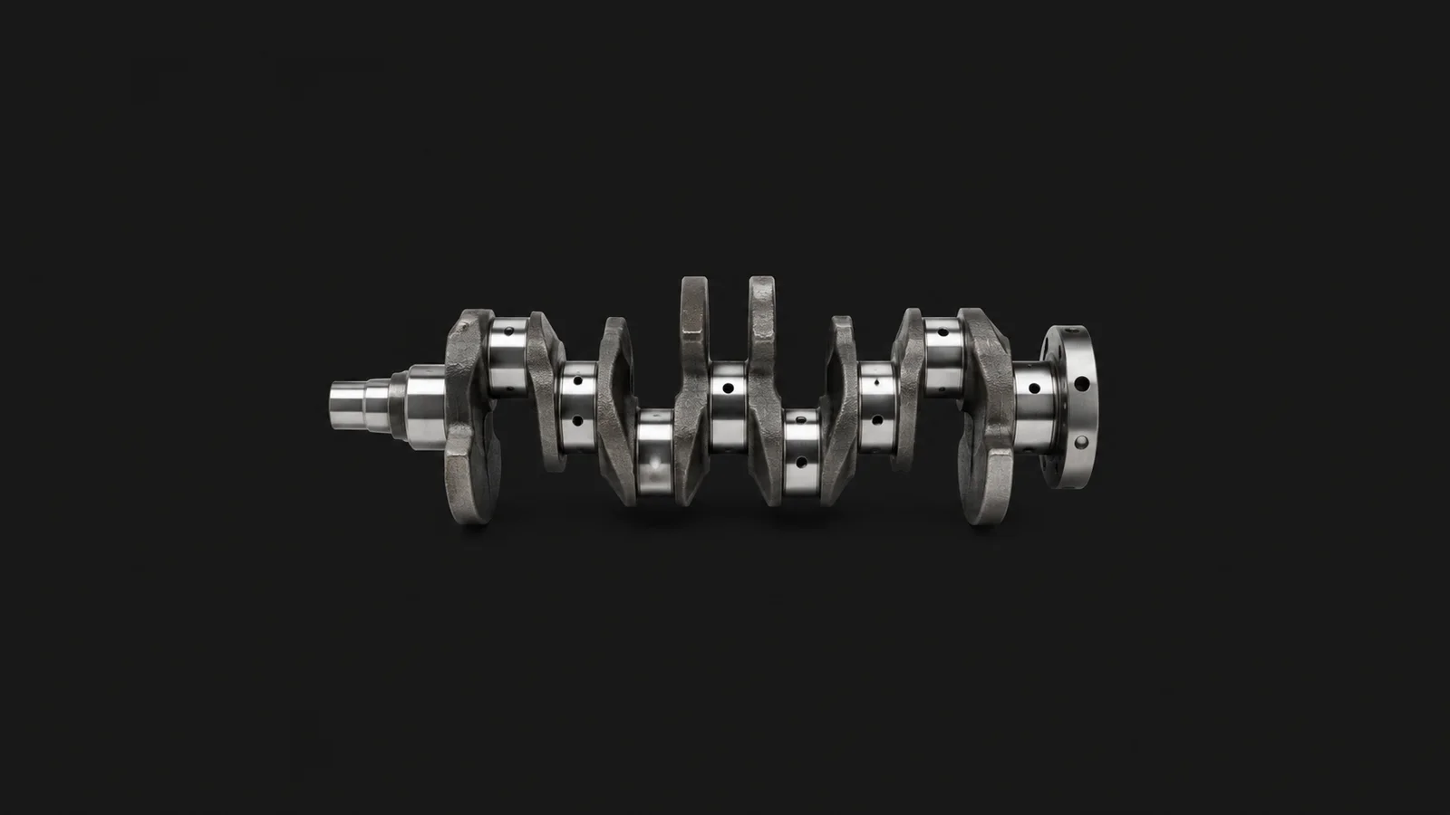 Isolated a car crankshaft with polished journals centred on a seamless deep charcoal near-black studio background, generous empty margin on every side for overlaid branding