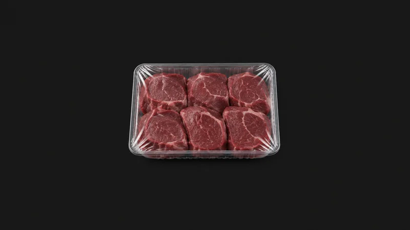 Isolated a clear shrink-wrapped tray of portioned product centred on a seamless deep charcoal near-black studio background, generous empty margin on every side for overlaid branding