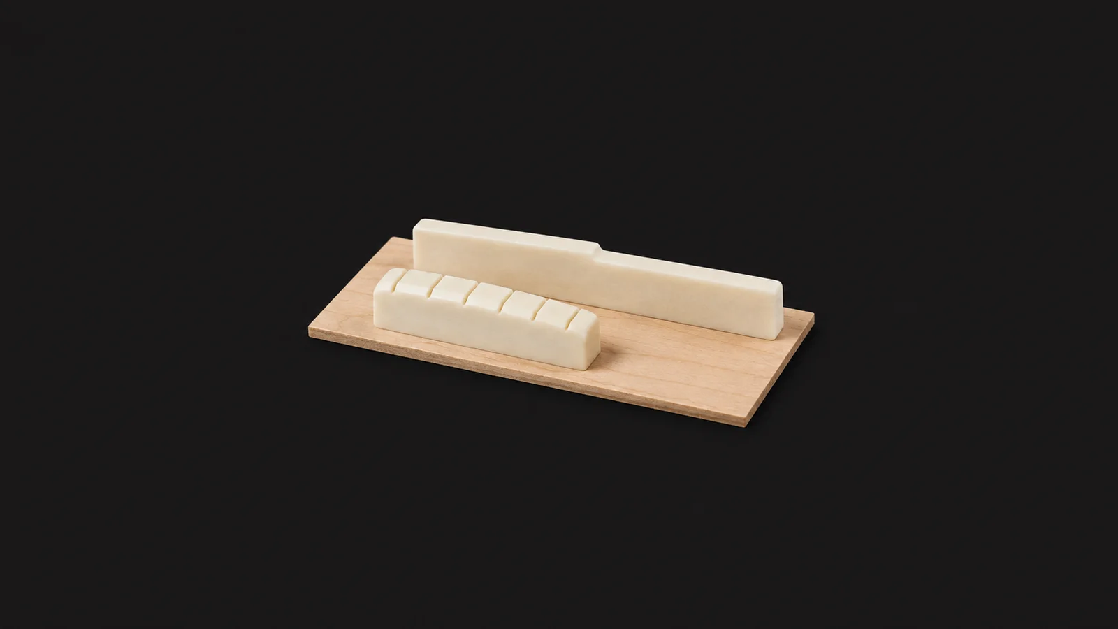 Isolated a bone nut and saddle blanks laid on a maple shim centred on a seamless deep charcoal near-black studio background, generous empty margin on every side for overlaid branding