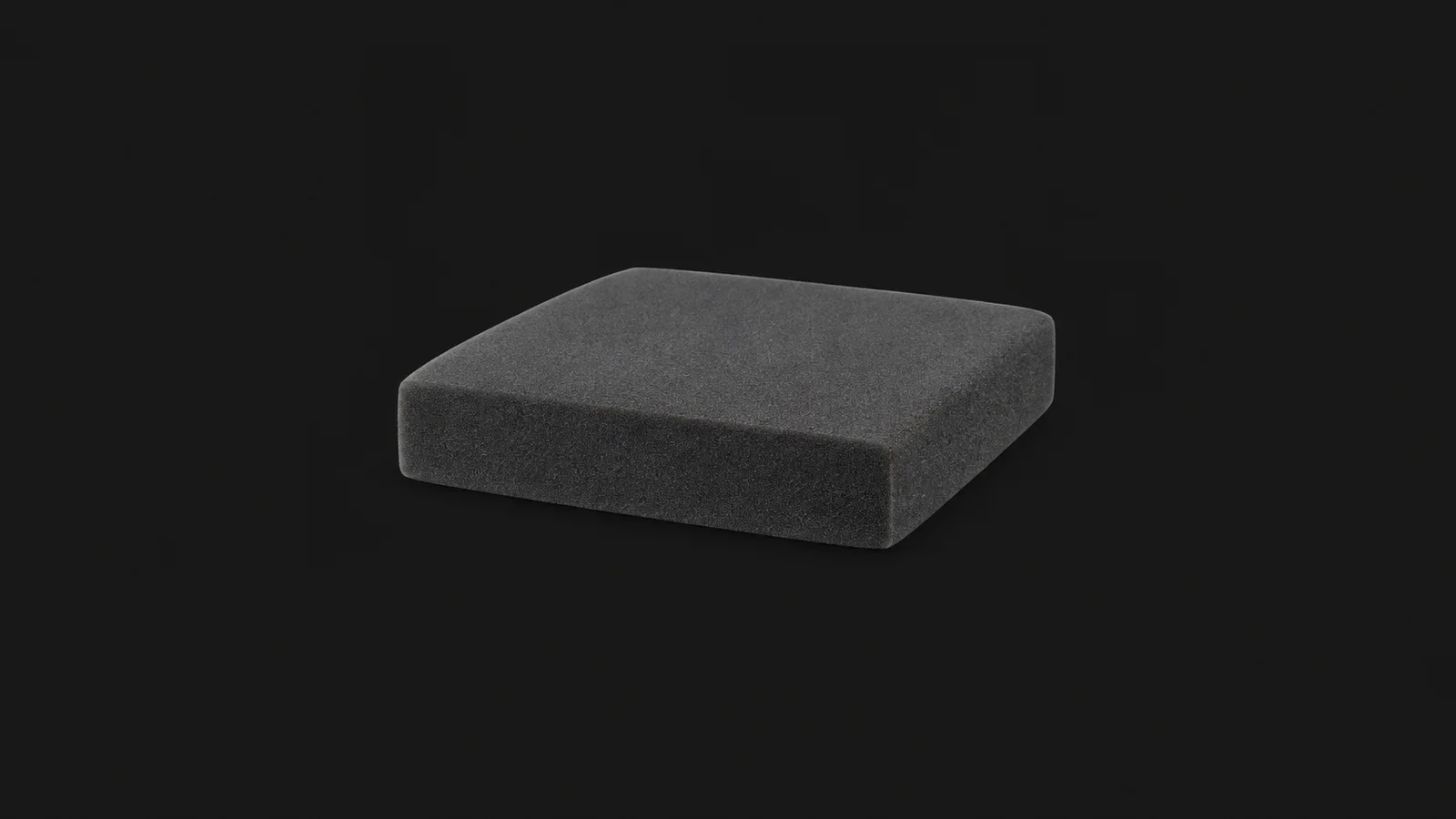 Isolated a slab of high-density foam cut to a cushion shape centred on a seamless deep charcoal near-black studio background, generous empty margin on every side for overlaid branding