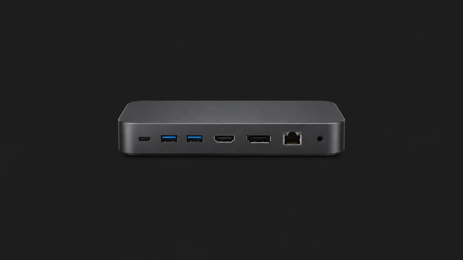 Isolated a laptop docking station with its ports facing out centred on a seamless deep charcoal near-black studio background, generous empty margin on every side for overlaid branding
