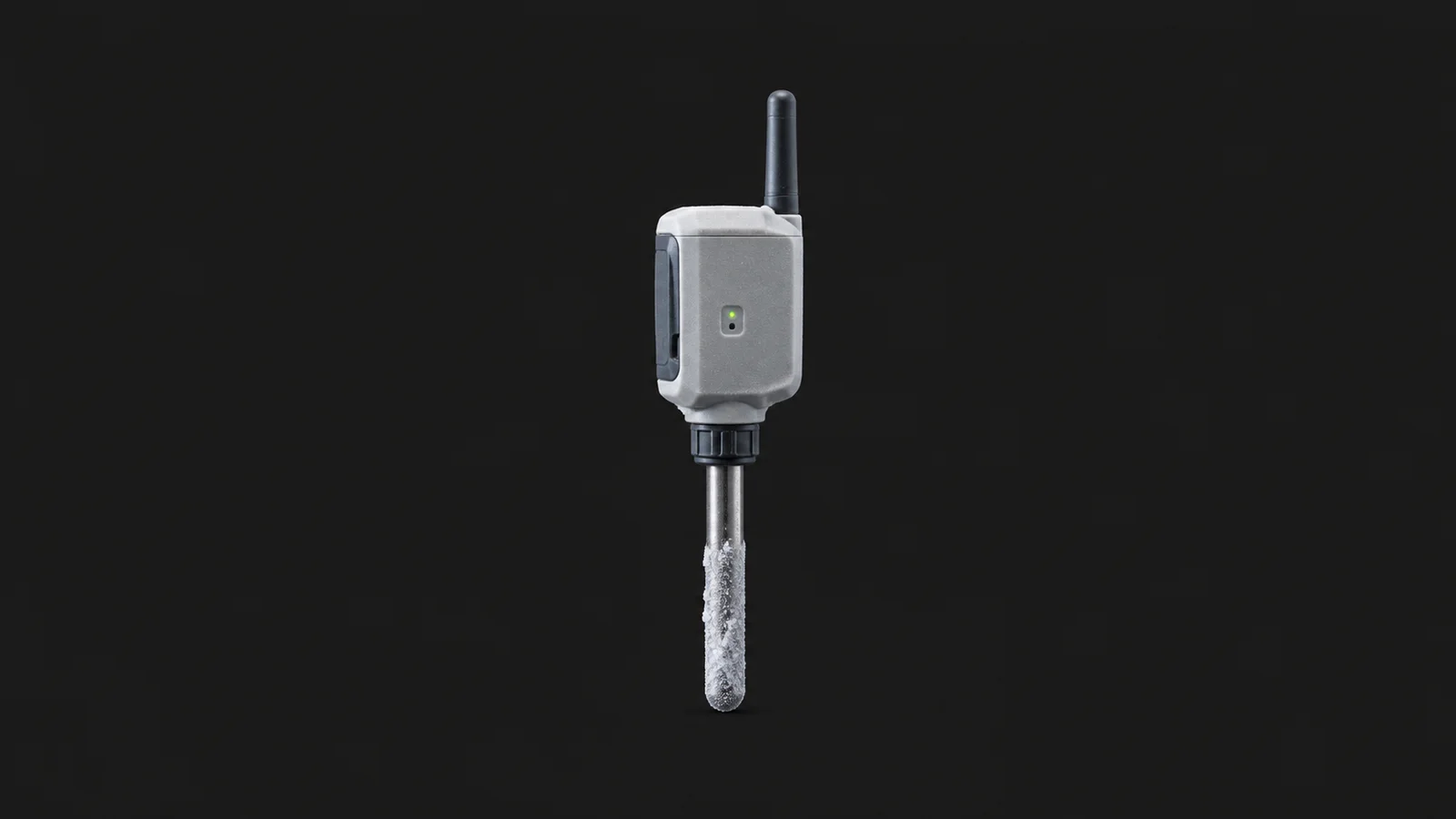 Isolated a wireless cold-chain temperature probe with a frost-crusted sensor tip centred on a seamless deep charcoal near-black studio background, generous empty margin on every side for overlaid branding