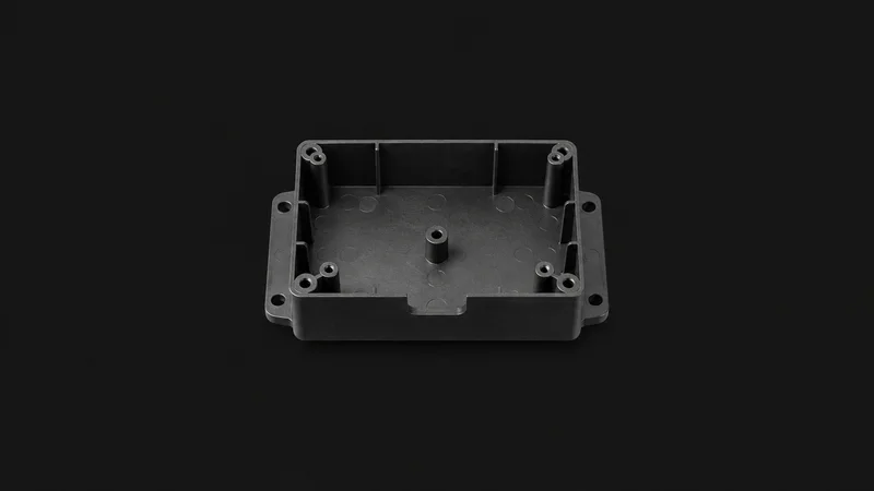 Isolated a moulded plastic housing with ejector-pin marks visible centred on a seamless deep charcoal near-black studio background, generous empty margin on every side for overlaid branding