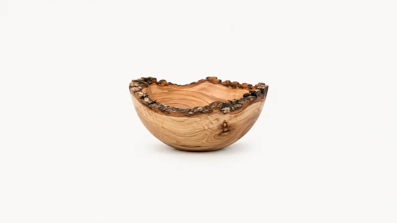 Isolated a turned wooden bowl with a bark edge centred on a seamless pale off-white studio background, generous empty margin on every side for overlaid branding