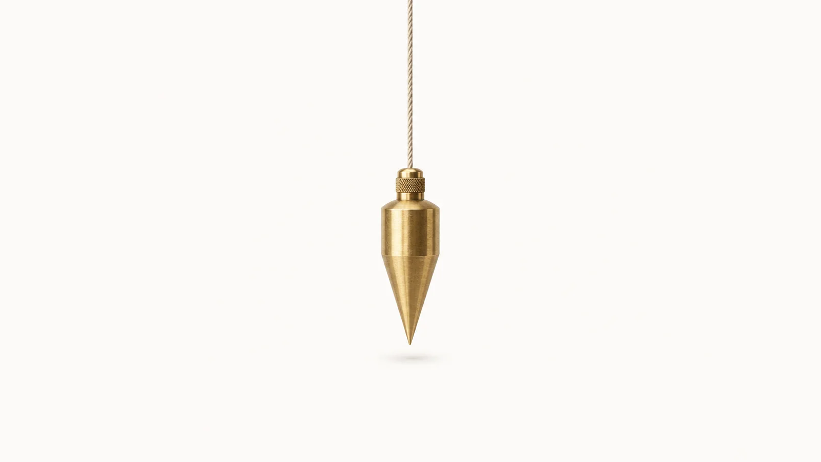 Isolated a surveyor's plumb bob of brass on a cord centred on a seamless pale off-white studio background, generous empty margin on every side for overlaid branding