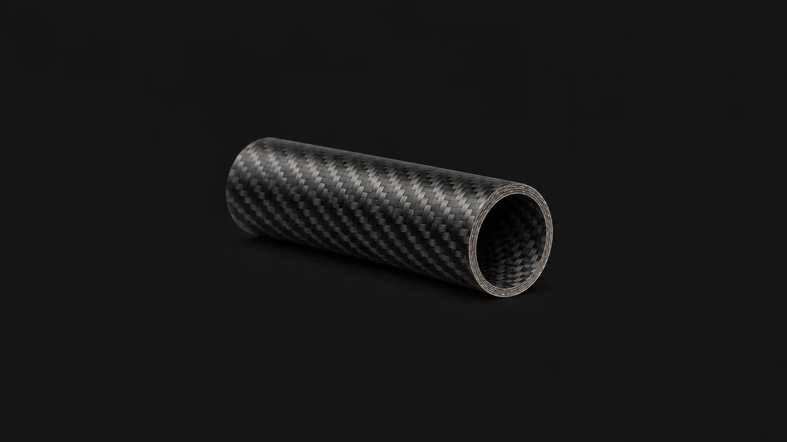 Isolated a carbon-fibre tube with a cut end showing plies centred on a seamless deep charcoal near-black studio background, generous empty margin on every side for overlaid branding