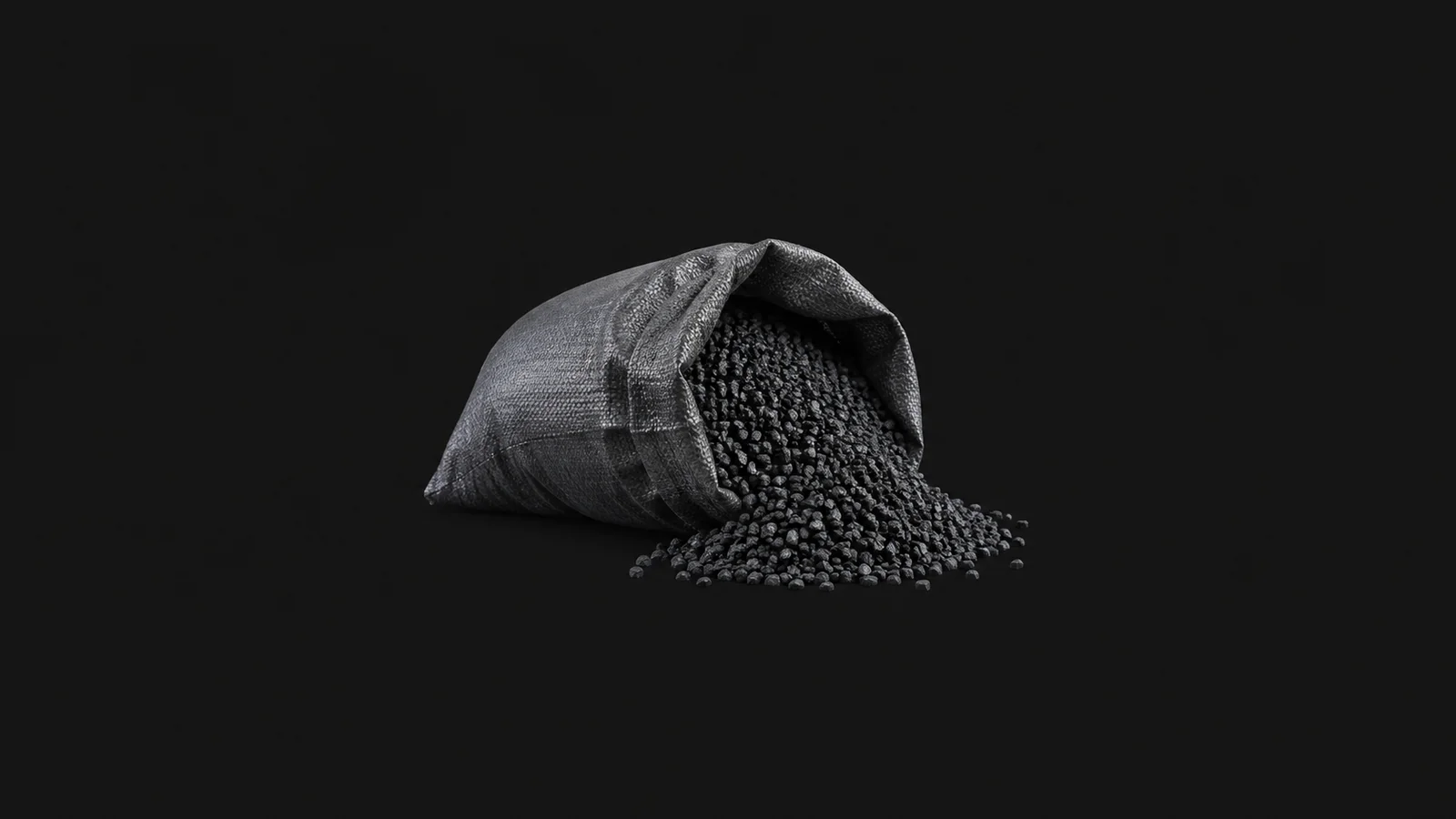 Isolated a bag of granular activated carbon spilling out centred on a seamless deep charcoal near-black studio background, generous empty margin on every side for overlaid branding