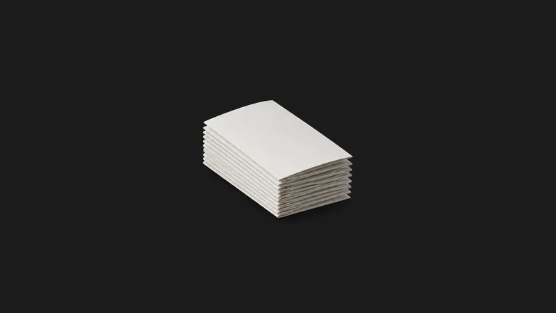 Isolated a trimmed stack of folded tri-fold leaflets centred on a seamless deep charcoal near-black studio background, generous empty margin on every side for overlaid branding