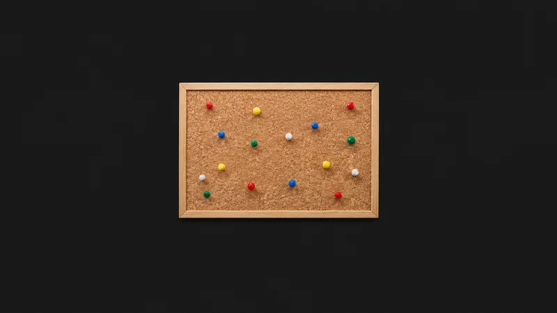 Isolated a cork pinboard with an array of coloured push pins centred on a seamless deep charcoal near-black studio background, generous empty margin on every side for overlaid branding