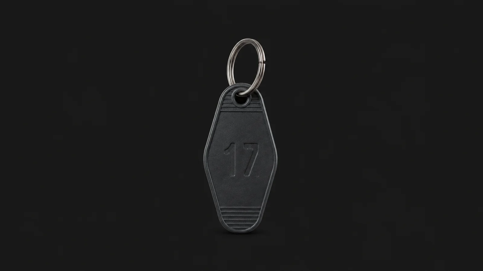 Isolated a numbered plastic key tag on a metal split ring centred on a seamless deep charcoal near-black studio background, generous empty margin on every side for overlaid branding