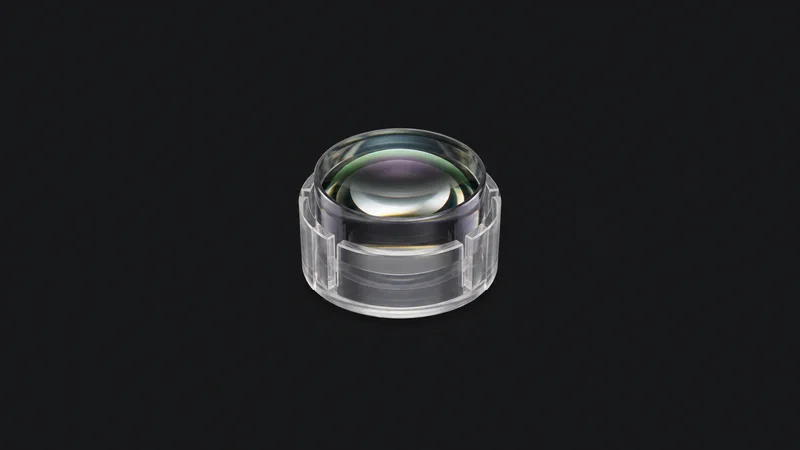 Isolated a cylindrical lens in a clear protective holder centred on a seamless deep charcoal near-black studio background, generous empty margin on every side for overlaid branding