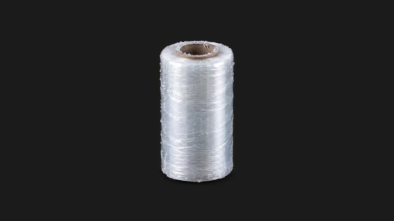 Isolated a frozen pallet-wrap roll with a rime of ice on its cardboard core centred on a seamless deep charcoal near-black studio background, generous empty margin on every side for overlaid branding