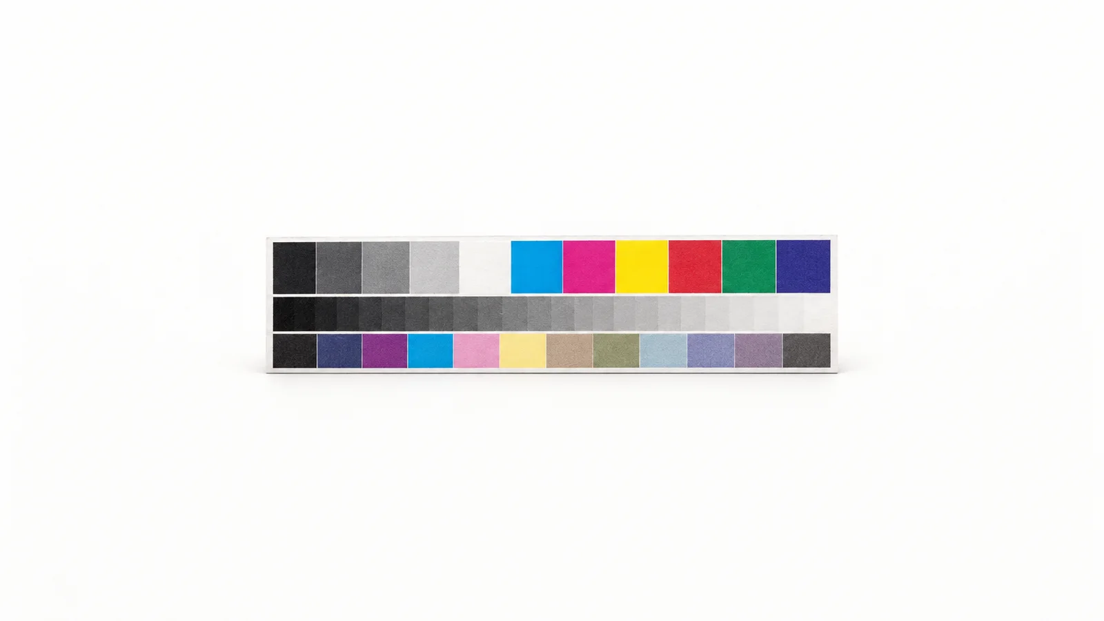 Isolated a printer colour-calibration test strip with density patches centred on a seamless pale off-white studio background, generous empty margin on every side for overlaid branding