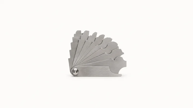 Isolated a fillet-weld gauge set centred on a seamless pale off-white studio background, generous empty margin on every side for overlaid branding