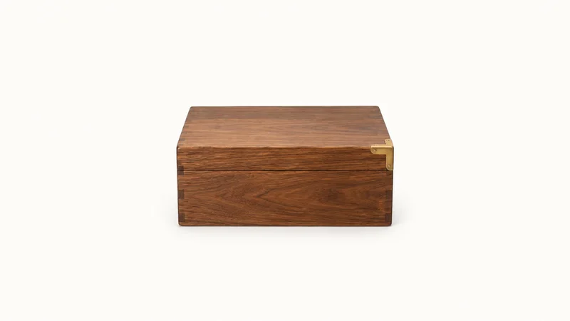 Isolated a wooden document box with a brass corner plate centred on a seamless pale off-white studio background, generous empty margin on every side for overlaid branding