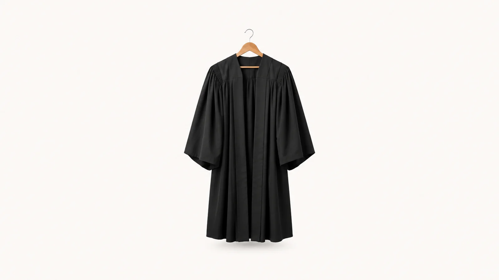 Isolated a black barrister's gown folded over a wooden hanger centred on a seamless pale off-white studio background, generous empty margin on every side for overlaid branding