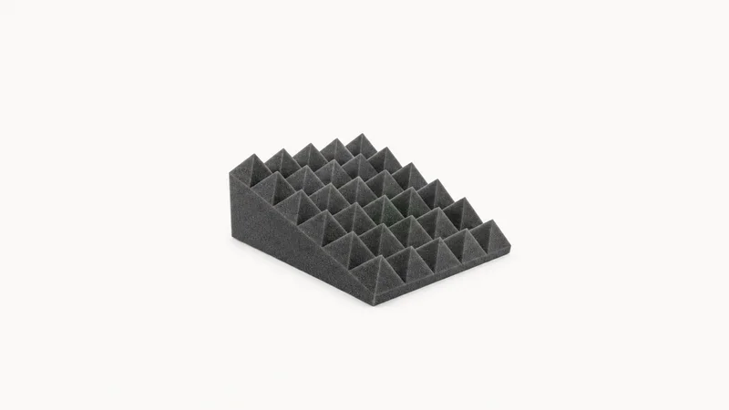 Isolated a wedge of acoustic foam with a pyramid surface centred on a seamless pale off-white studio background, generous empty margin on every side for overlaid branding
