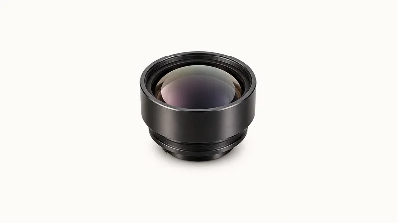 Isolated an infrared germanium lens with a dark metallic sheen centred on a seamless pale off-white studio background, generous empty margin on every side for overlaid branding