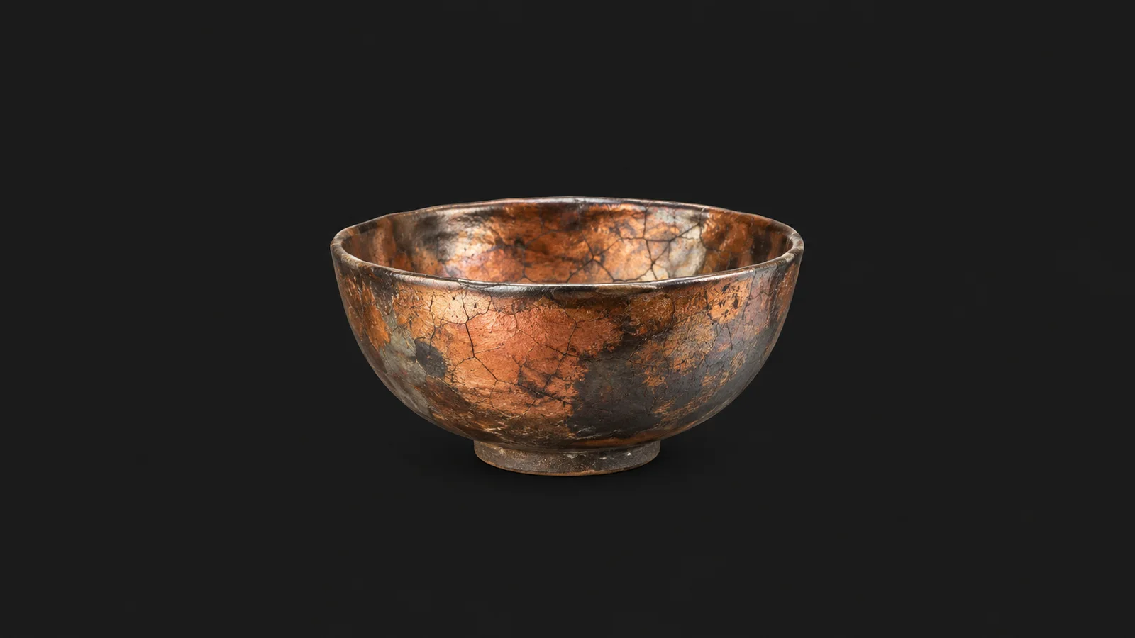 Isolated a raku-fired bowl with a crackled copper glaze centred on a seamless deep charcoal near-black studio background, generous empty margin on every side for overlaid branding